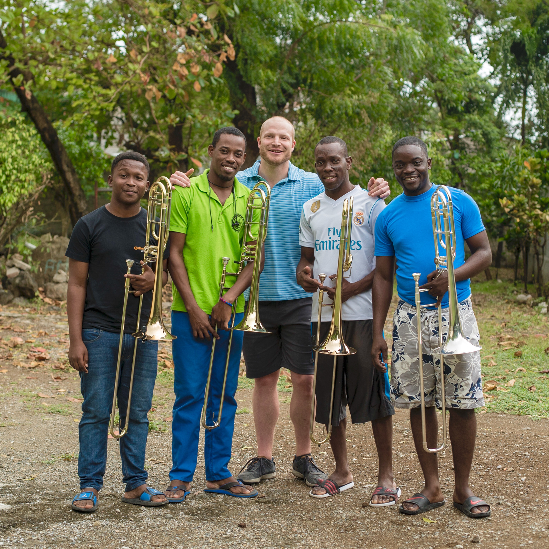 Mark Davidson stands with 4 Haitian trombonists