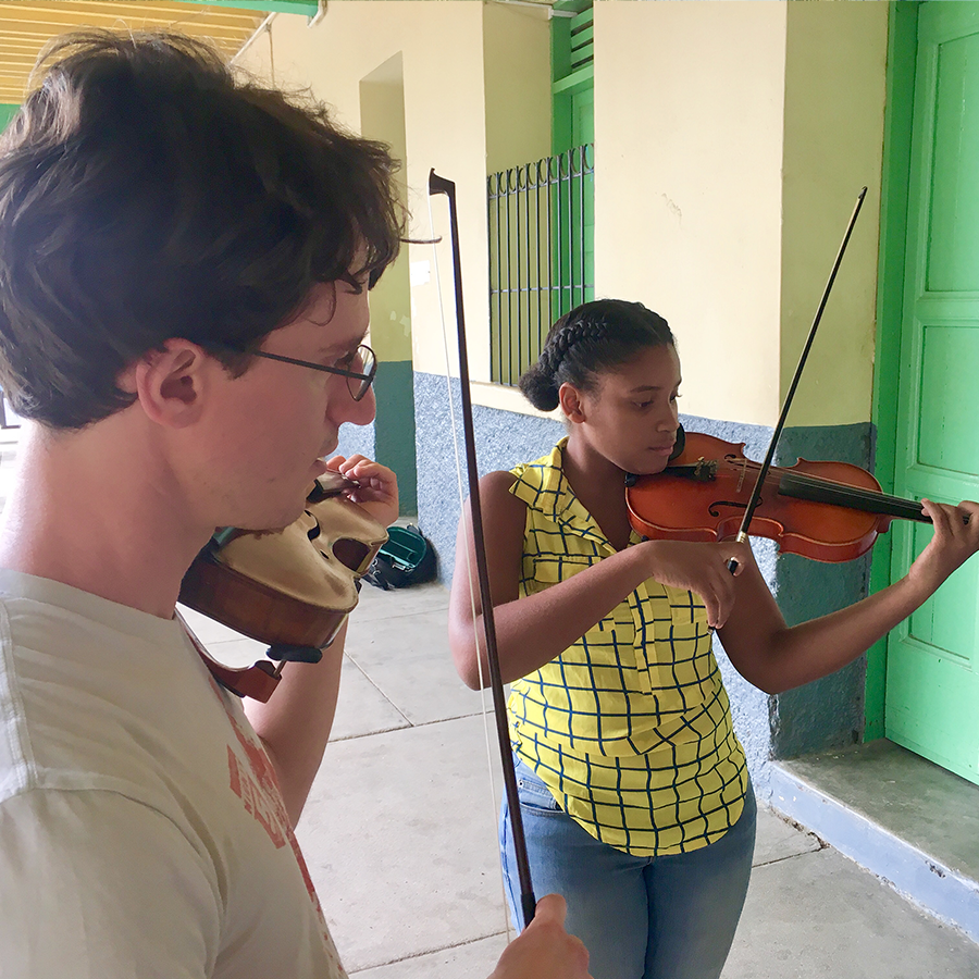 A Utah Symphony member instructs a Haitian violinist